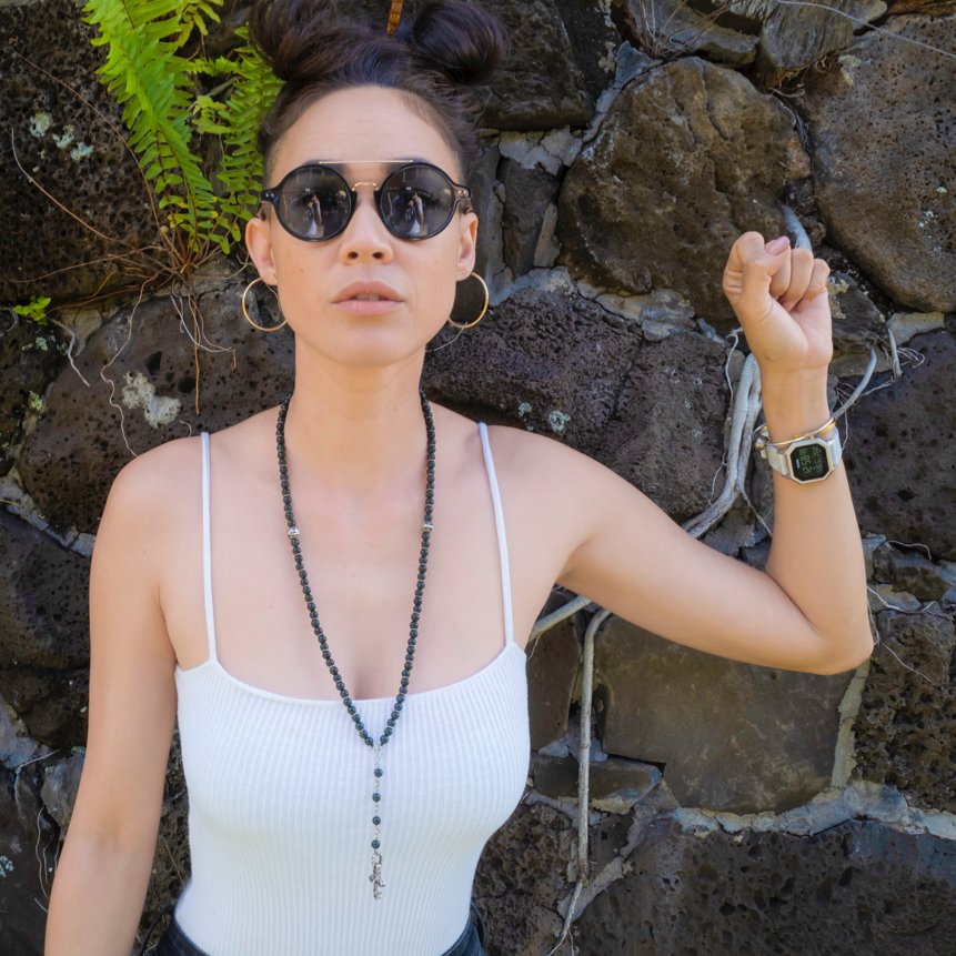 A young woman in sunglasses shows her Nixon Staple digital watch.